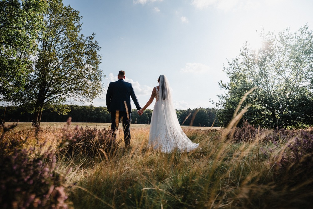 Brautpaar blickt auf ein Feld bei Sonnenschein vom Hochzeitsfotograf Stephan Gröger aus Hannover